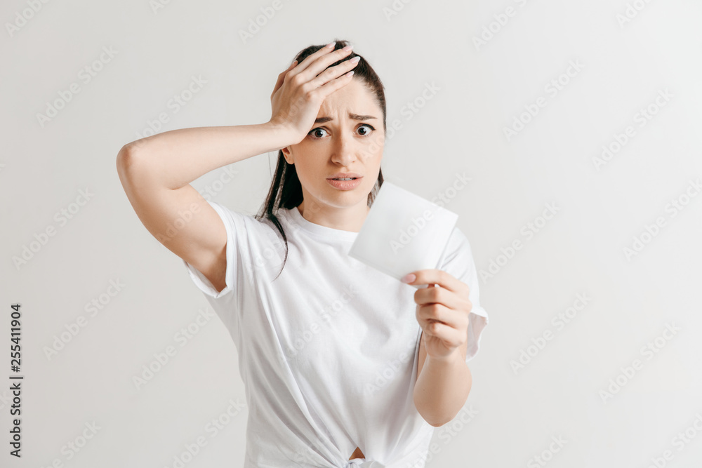 Young woman with a surprised unhappy expression lost a bet on studio background. Human facial emotions and betting concept. Trendy colors.