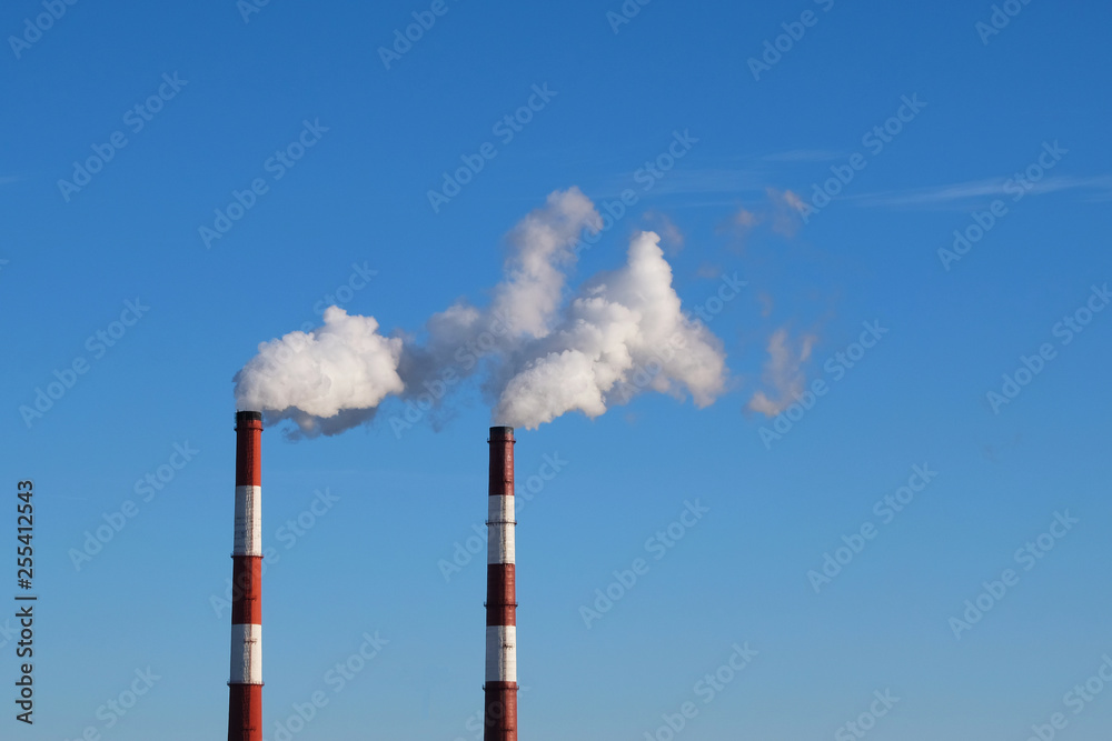 Pipes in the city with smoke, against a blue sky background. Environmental problem of environmental pollution and air in large cities. Pipes in the city with smoke, against a blue sky background. Environmental problem of environmental pollution and air in large cities.