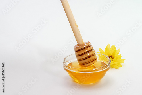 honey dipper takes honey from a bowl full of honey on a white background.