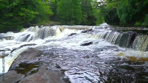 A waterfall flows quickly in Michigan after a heavy rain along a hiking trail in the mountains