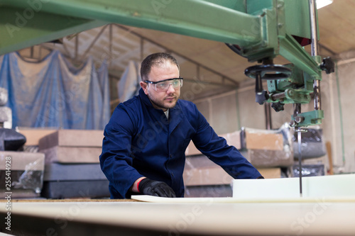 Young man in a furniture factory is cutting the foam for the sofa