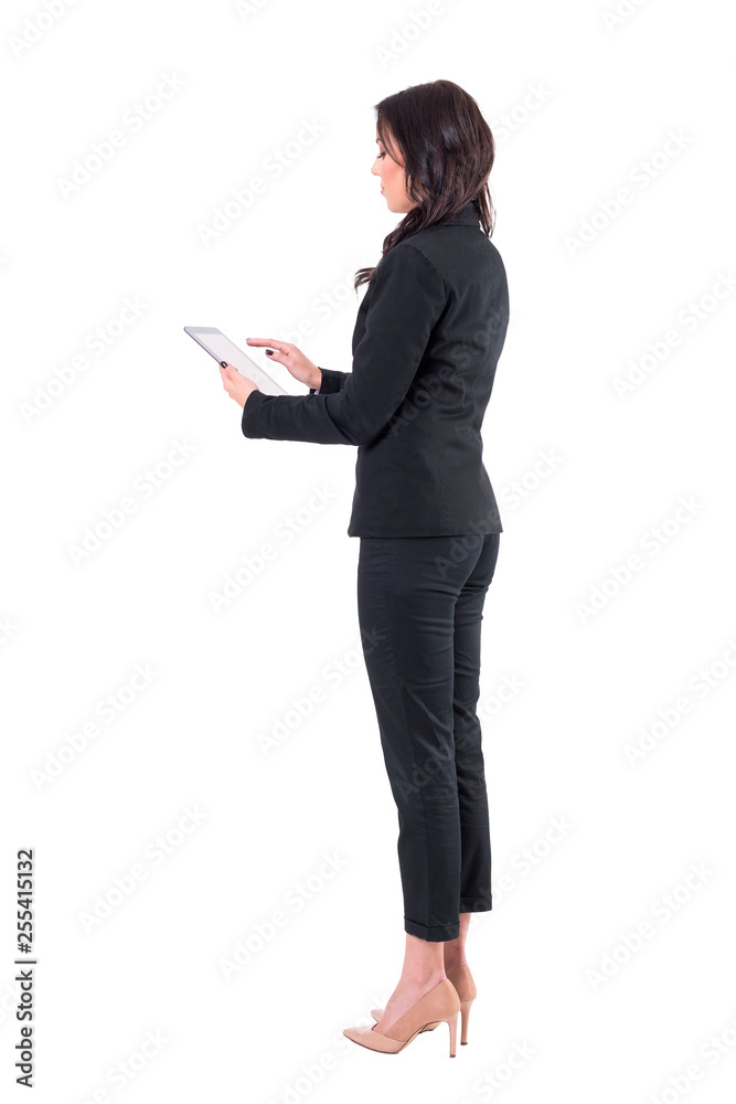 Side view of business woman in black suit working on tablet computer. Full body isolated on white background. Side view of business woman in black suit working on tablet computer. Full body isolated on white background.
