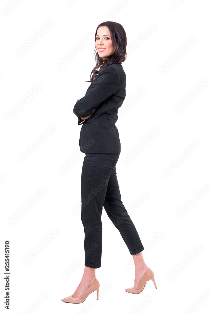 Side view of happy successful business woman with crossed hands walking and smiling at camera. Full body isolated on white background. Side view of happy successful business woman with crossed hands walking and smiling at camera. Full body isolated on white background.