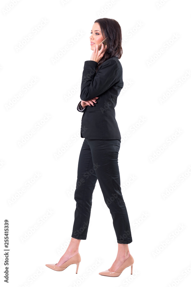 Side view of busy business woman walking and communicating on cellphone. Full body isolated on white background. Side view of busy business woman walking and communicating on cellphone. Full body isolated on white background.