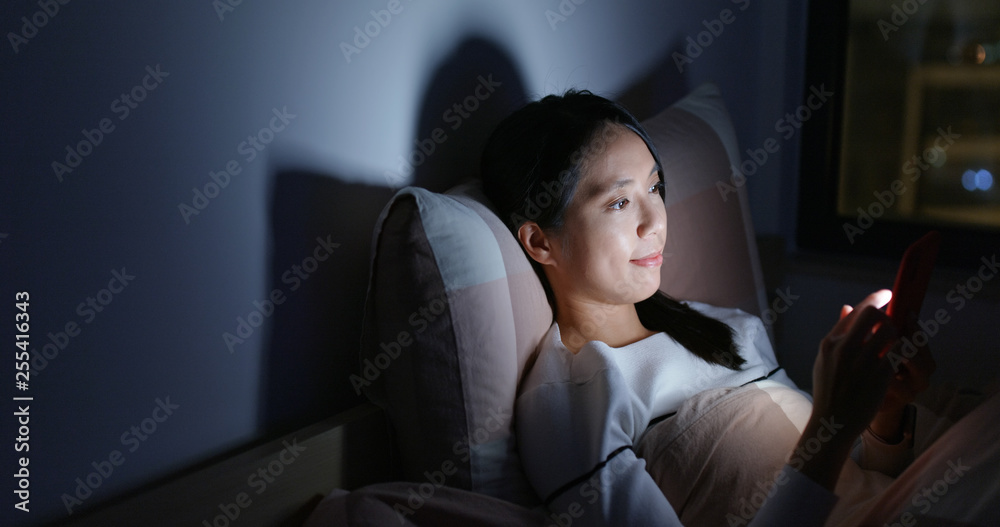 Obraz premium Woman use of mobile phone on bed at night