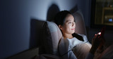 Woman use of mobile phone on bed at night