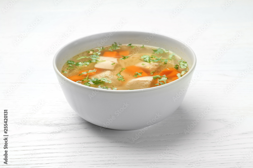 Bowl with fresh homemade chicken soup on wooden table