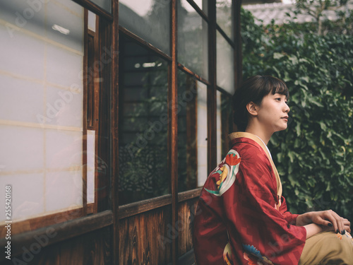 Side view of thoughtful young woman in kimono sitting outdoors photo