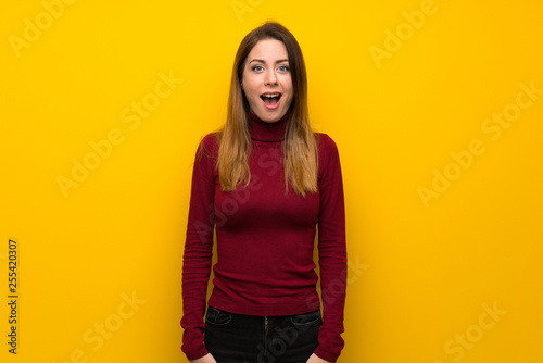 Woman with turtleneck over yellow wall with surprise facial expression