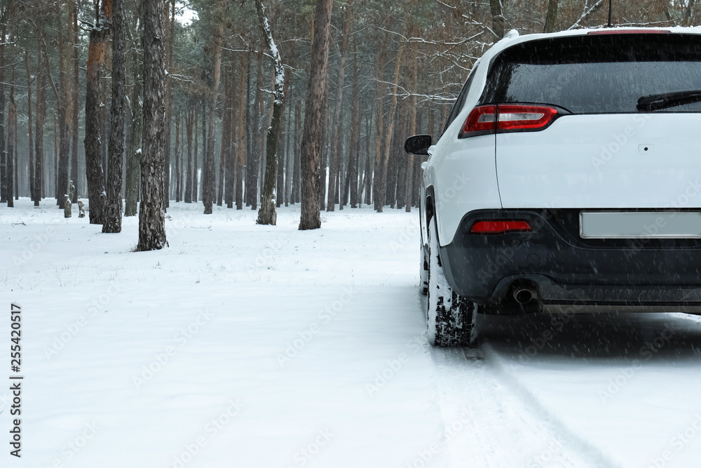 Modern car on snowy road in forest. Space for text Modern car on snowy road in forest. Space for text