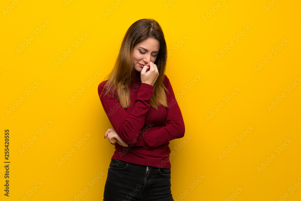 Woman with turtleneck over yellow wall having doubts Woman with turtleneck over yellow wall having doubts