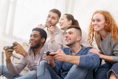 Excited friends playing video games at home