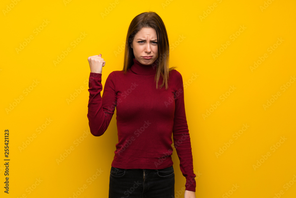 Woman with turtleneck over yellow wall with angry gesture Woman with turtleneck over yellow wall with angry gesture