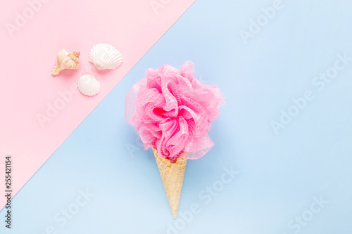 Composition of ice cream cone with pink wisp of bast on a light blue background. Bathroom cosmetic accessories. Flat Lay. Top View