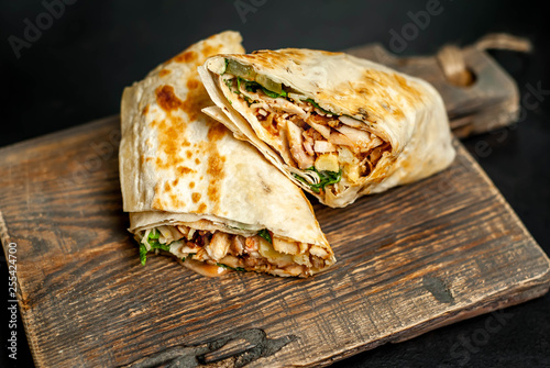 Burrito wraps with chicken and vegetables on a cutting board  against a background of concrete  Mexican shawarma
