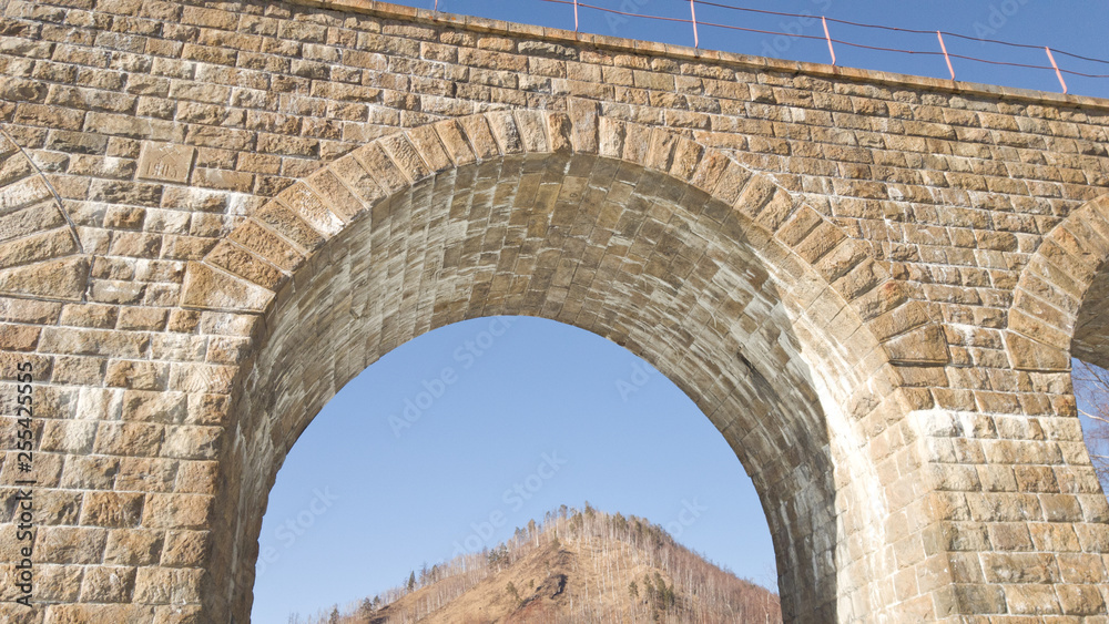One of the old beautiful arches on the Circum-Baikal railway off the shores of lake Baikal in the spring. In the background you can see the hill