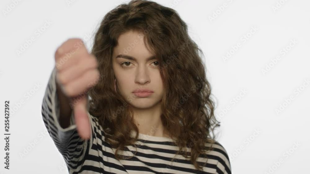 Upset woman showing thumbs down in studio. Unhappy girl showing dislike gesture