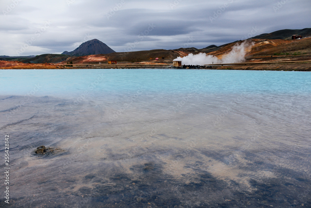 Blue lagoon in Iceland with active volcano on background