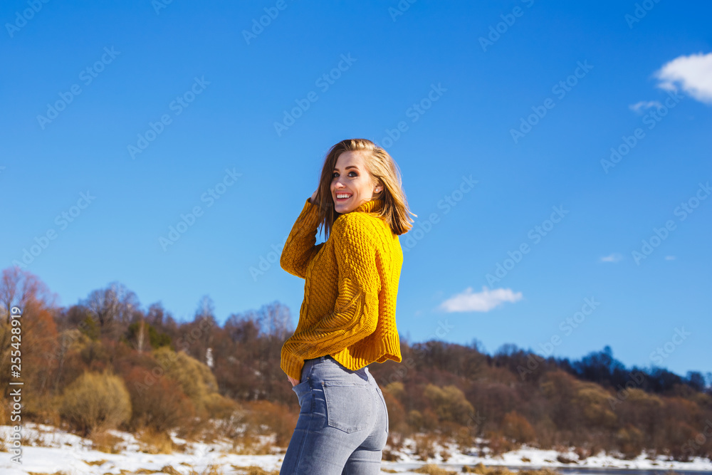Girl in a yellow sweater posing against the blue sky and winter forest Girl in a yellow sweater posing against the blue sky and winter forest