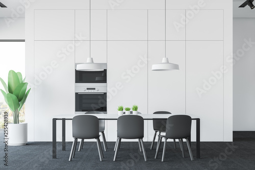 Interior of white kitchen with table and ovens © ImageFlow