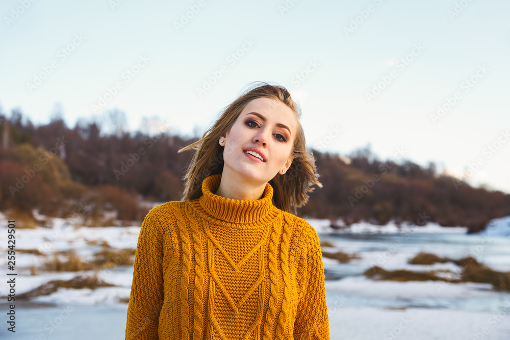 Portrait of a girl in a yellow sweater and short hair against a blue sky and winter forest Portrait of a girl in a yellow sweater and short hair against a blue sky and winter forest