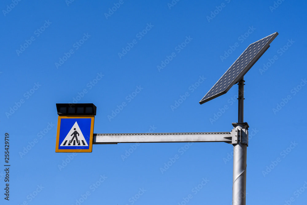 Sign of crossing of pedestrians with lights activated by a solar panel display in Bucharest, Romania, on clear blue sky Sign of crossing of pedestrians with lights activated by a solar panel display in Bucharest, Romania, on clear blue sky