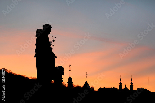 Sights of Prague, Czech Republic. Beautiful landscape silhouettes of sculptures against sky. Sunset backlit silhouettes of statues and roofs on hill background of cityscape skyline at Charles Bridge.