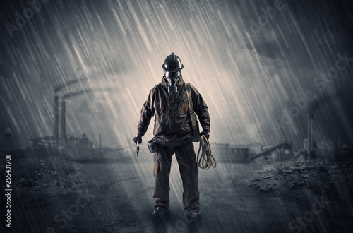 Gas masked survival man coming with arms on his hand in a demolished dark environment 