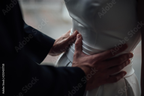 The groom gently holds the bride by the waist.