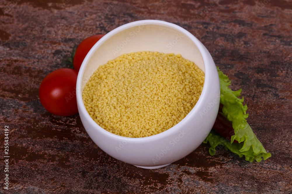 Raw couscous in the bowl served salad leaves, tomato and pepper Raw couscous in the bowl served salad leaves, tomato and pepper