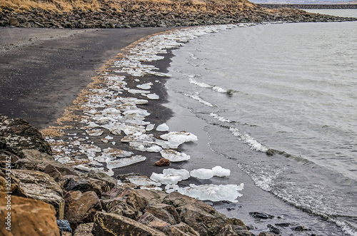 Large chuncks of ice on the black sandy beach of a little bay at a fjord near the town of Borgarnes, Iceland in winter photo