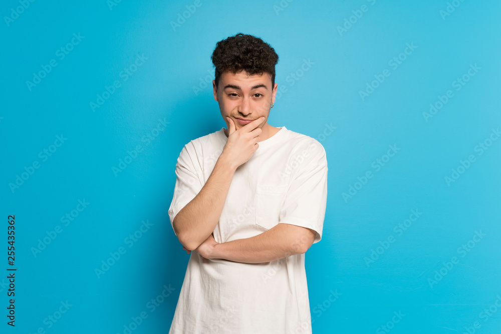 Young man over blue background looking to the front