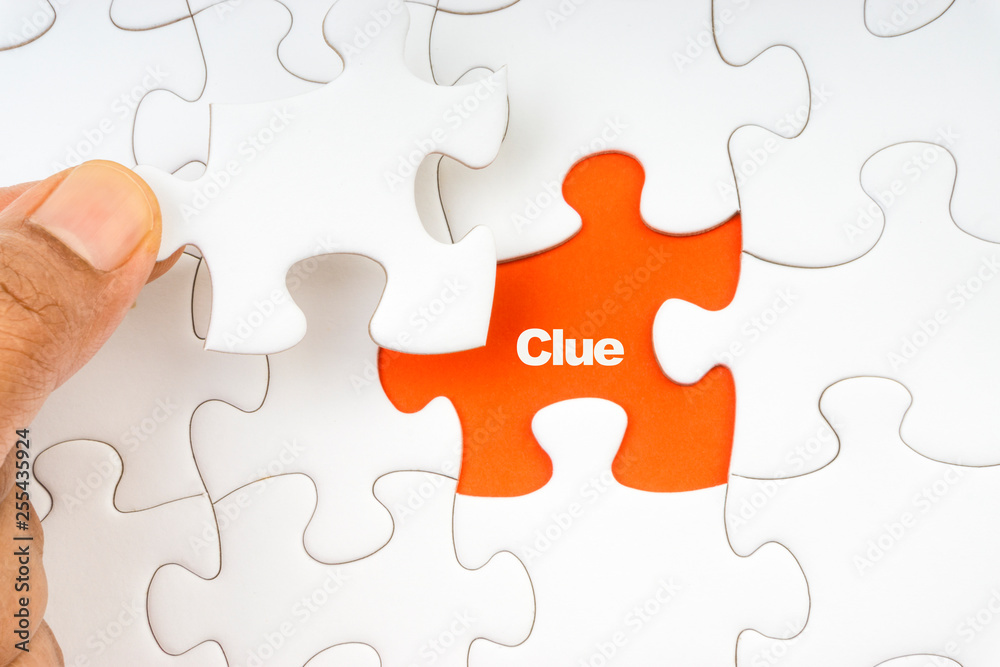 Hand holding piece of jigsaw puzzle with word CLUE. Selective focus Hand holding piece of jigsaw puzzle with word CLUE. Selective focus