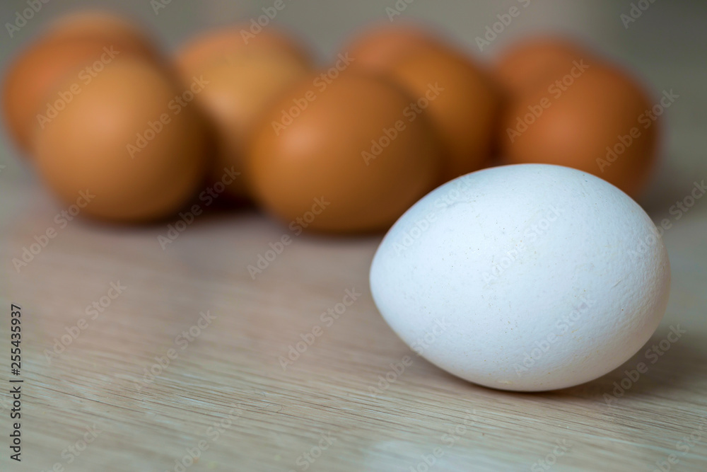 Big white egg and group of yellow eggs on kitchen table light background. Healthy organic food, delicious meal, cholesterol and diet concept. Big white egg and group of yellow eggs on kitchen table light background. Healthy organic food, delicious meal, cholesterol and diet concept.