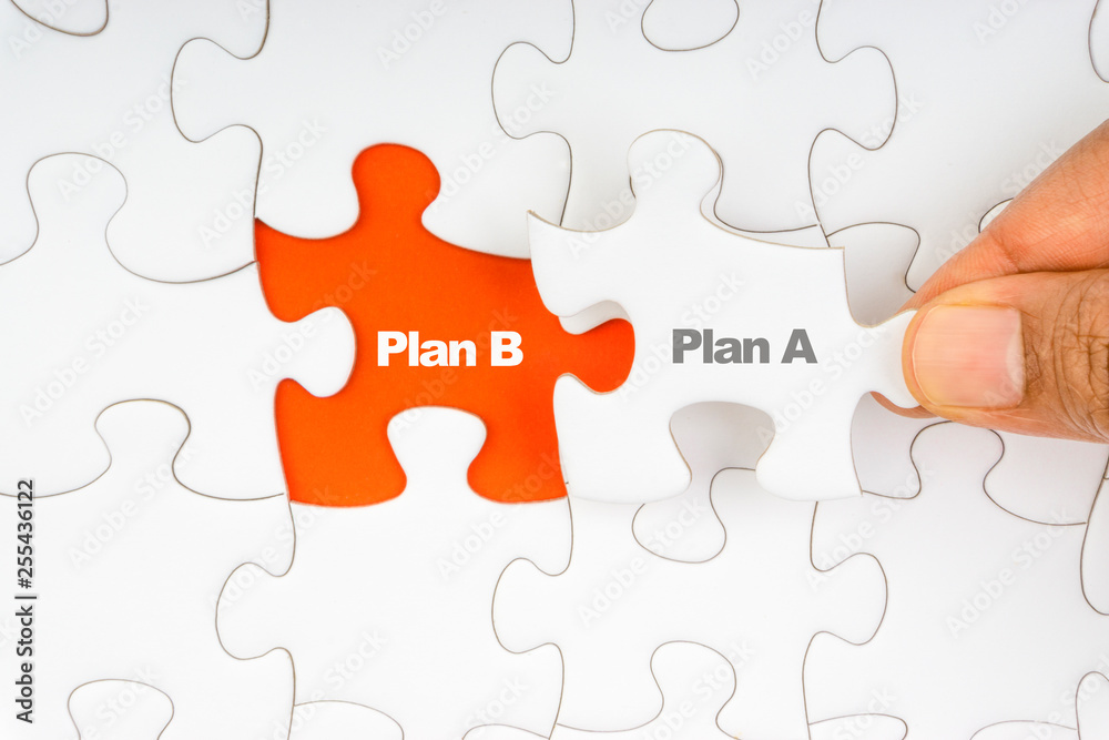 Fototapeta premium Hand holding piece of jigsaw puzzle with word PLAN A & PLAN B. Selective focus