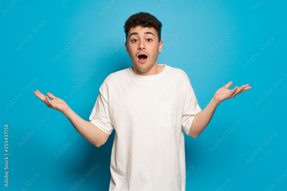 Young man over blue background with surprise and shocked facial expression