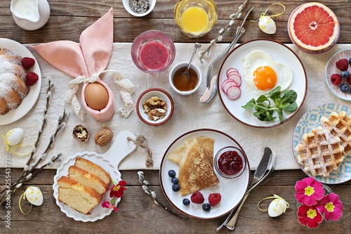 Easter festive breakfast or brunch set served on rustic wooden table. Overhead view, copy space