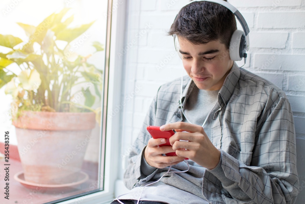 young with headphones and mobile phone in the window young with headphones and mobile phone in the window