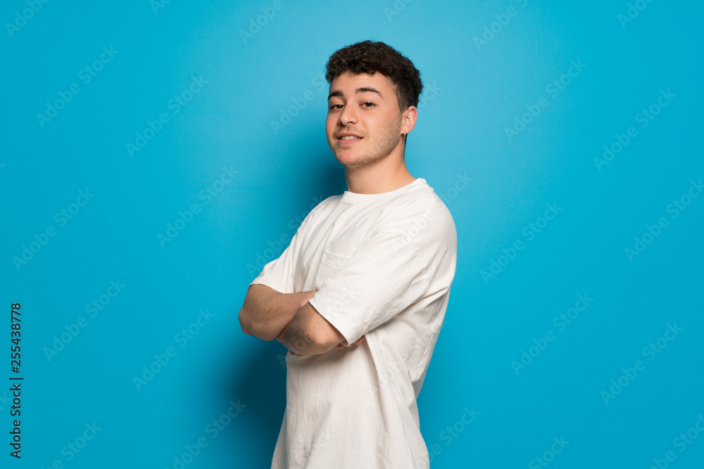 Young man over blue background with arms crossed Young man over blue background with arms crossed