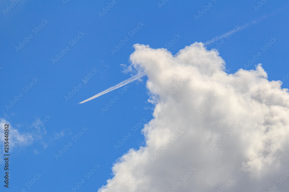 Jet aircraft with condensation trail on a blue sky with white clouds in sunny day Jet aircraft with condensation trail on a blue sky with white clouds in sunny day