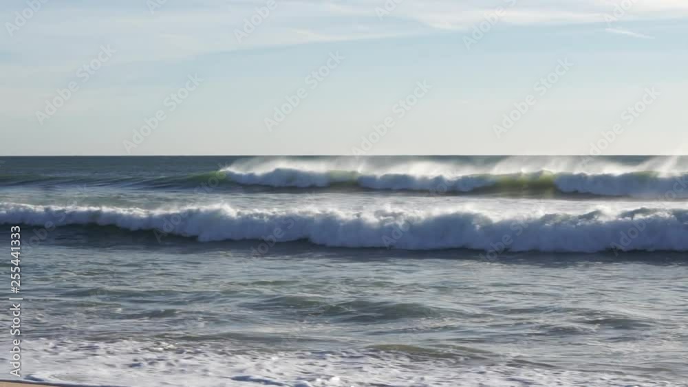 White waves breaking on beach slow motion pan right to left