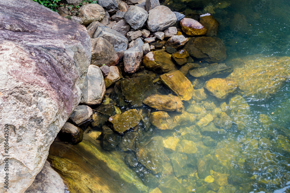 stones in the water are visible through the shallow water stones in the water are visible through the shallow water