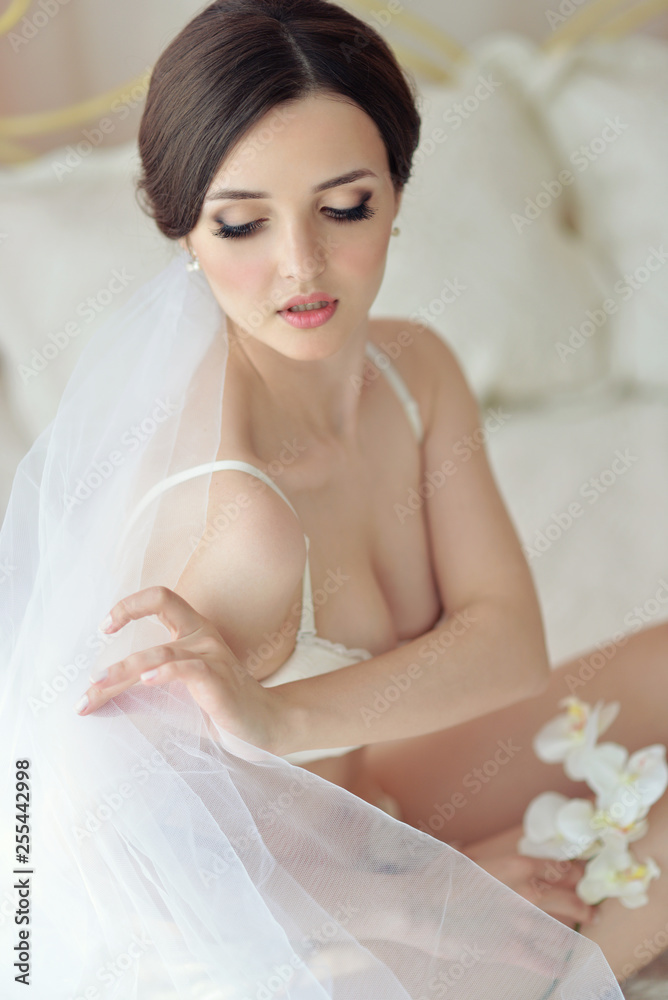 Young attractive female model girl before the wedding. Morning boudoir of the bride. Beautiful lingerie and white dress, delicate image Young attractive female model girl before the wedding. Morning boudoir of the bride. Beautiful lingerie and white dress, delicate image