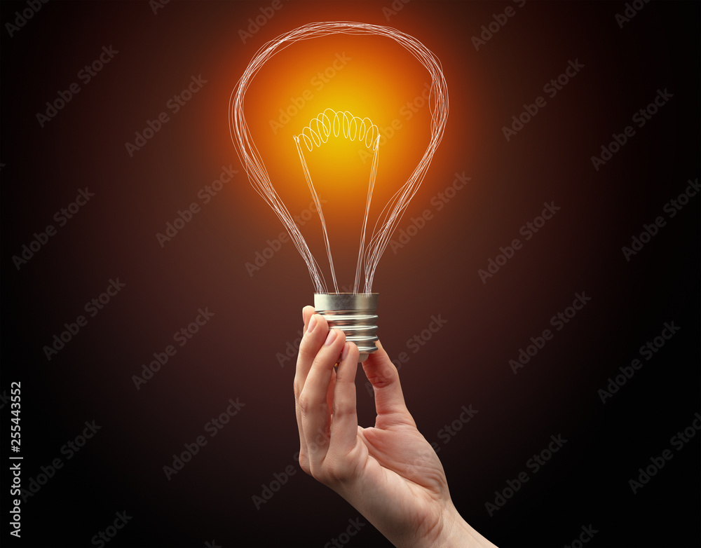 Hand holding light bulb on dark background. New idea concept Hand holding light bulb on dark background. New idea concept