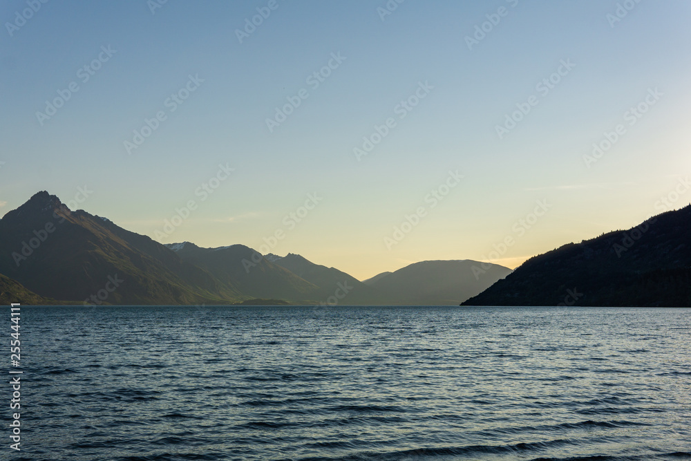 peaceful landscape during sunset with calm sky above the lake and mountain range