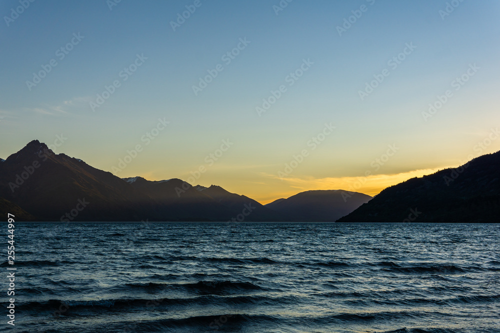 peaceful landscape during sunset with calm sky above the lake and mountain range