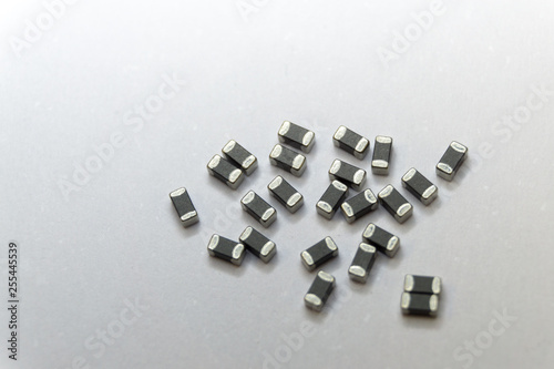 Abstract close-up of grey scattered 0402 SMT surface mount chip ferrite bead power electronics components on white background in random pattern