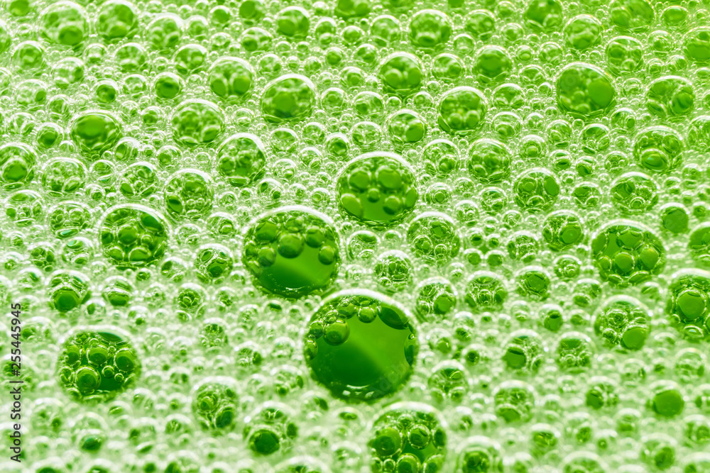 Macro image foam bubbles from soap or shampoo washing against a green background