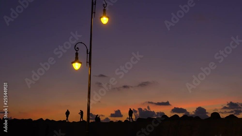 Amazing silhouettes of people strolling backlight at sunset