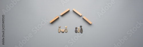 Two families made of pebbles under a roof made of wooden pegs